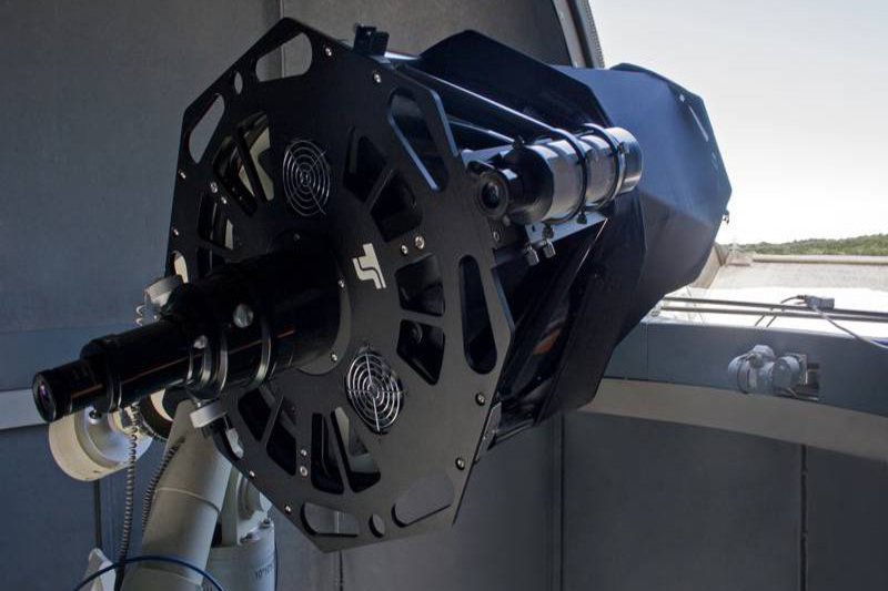 Ein massives schwarzes Teleskop ragt aus einem Fenster heraus.