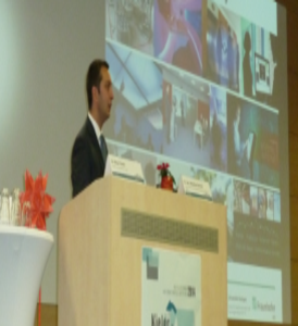 Ein Redner hält auf der Bühne seinen Vortrag.