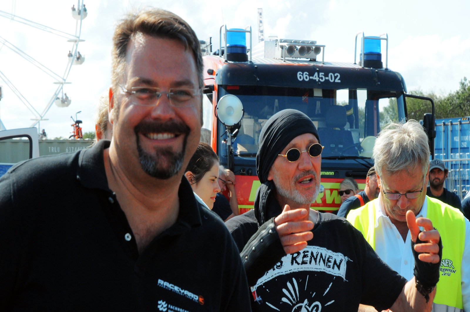 Ein Mann lächelt freudig in die Kamera, hinter ihm ist der Werner Erfinder, genannt Brösel zu sehen.