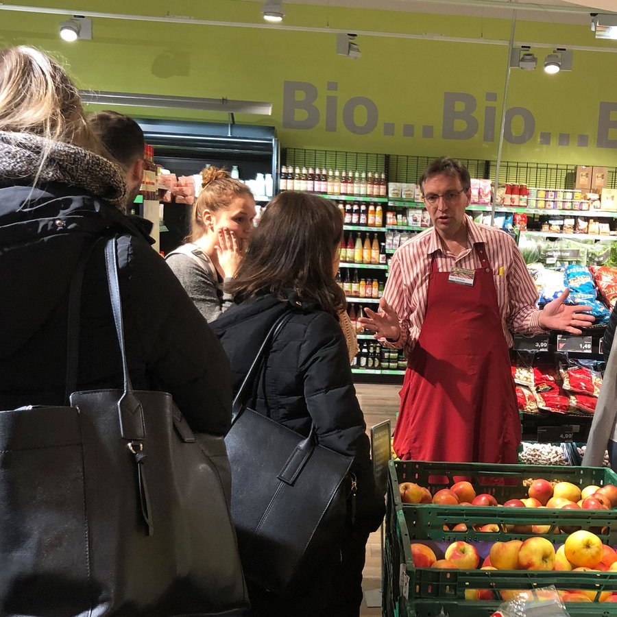 Verkäufer im Bioladen erklärt Gruppe etwas