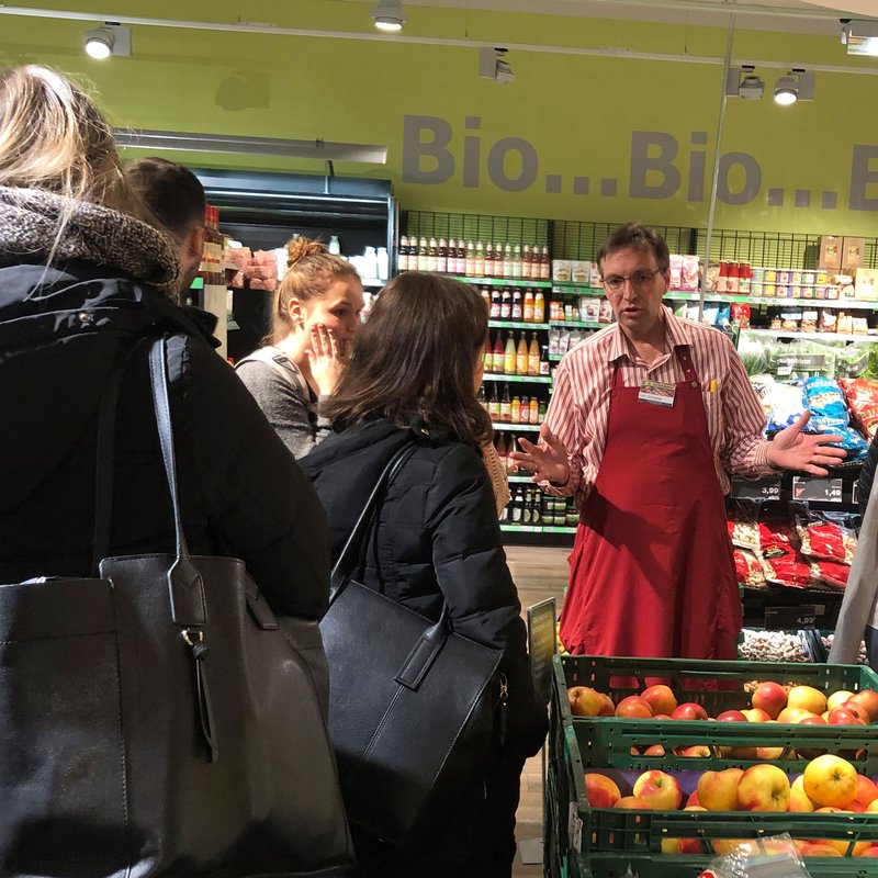 Verkäufer im Bioladen erklärt Gruppe etwas