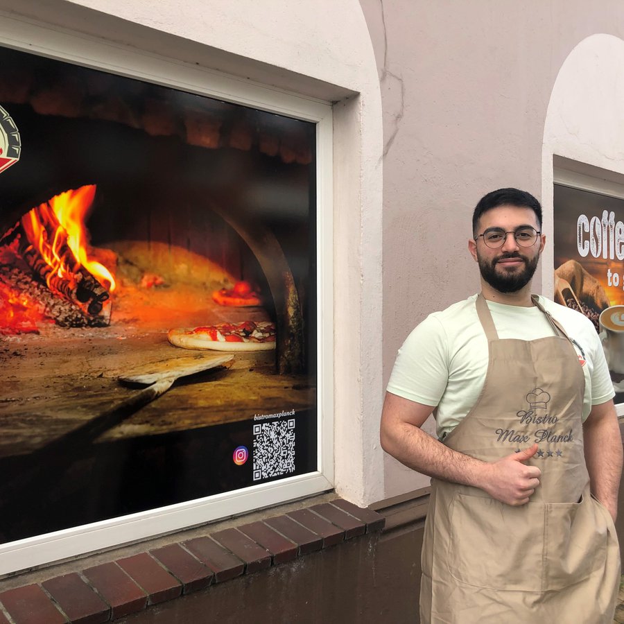 Foto: Meise ein Mann mit Schürze vor einem Gebäude
