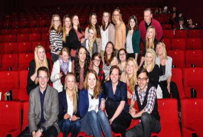 Viele Studentinnen und ein paar Studenten, posieren auf den roten Sesseln des Kinosaals.
