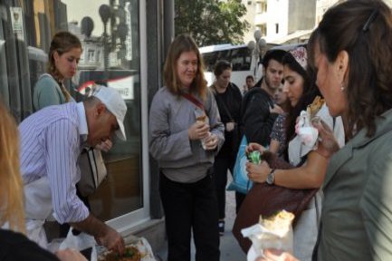 Eine Gruppe Studentinnen kauft etwas zu Essen bei einem Straßenhändler.
