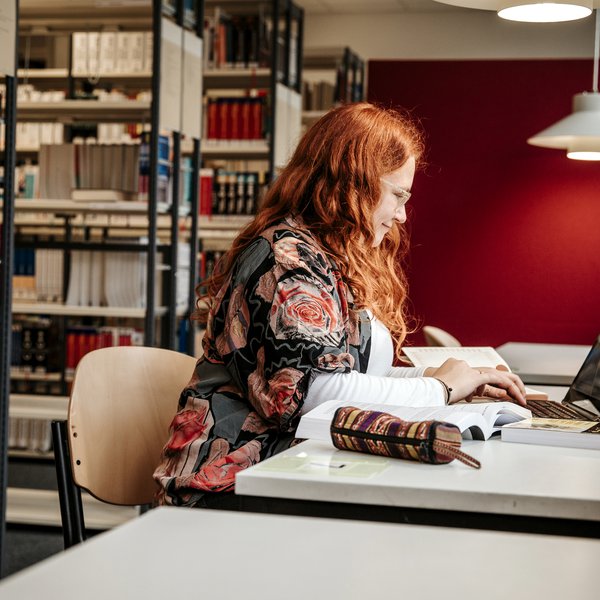 Studentin sitzt an Tisch. Vor ihr ein Laptop.