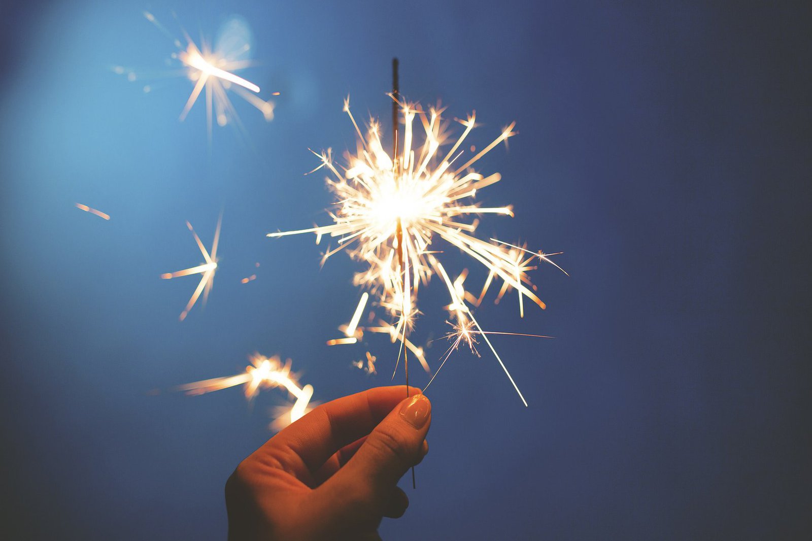 Eine brennende Wunderkerze, gehalten von einer Hand.