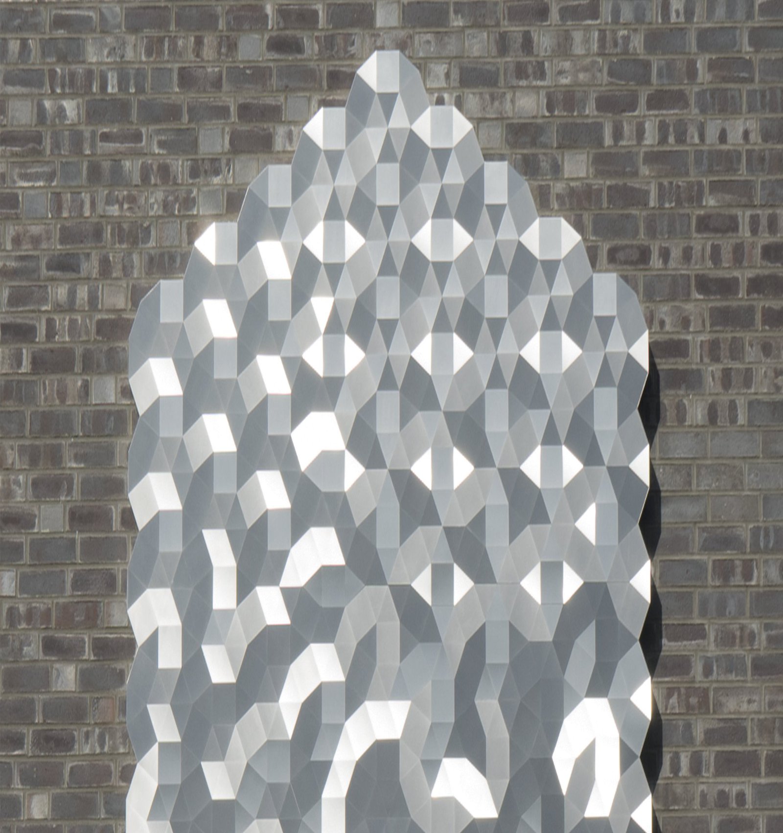 Das Bild zeigt eine verzierte Metallplatte, die an einer Steinwand hängt.