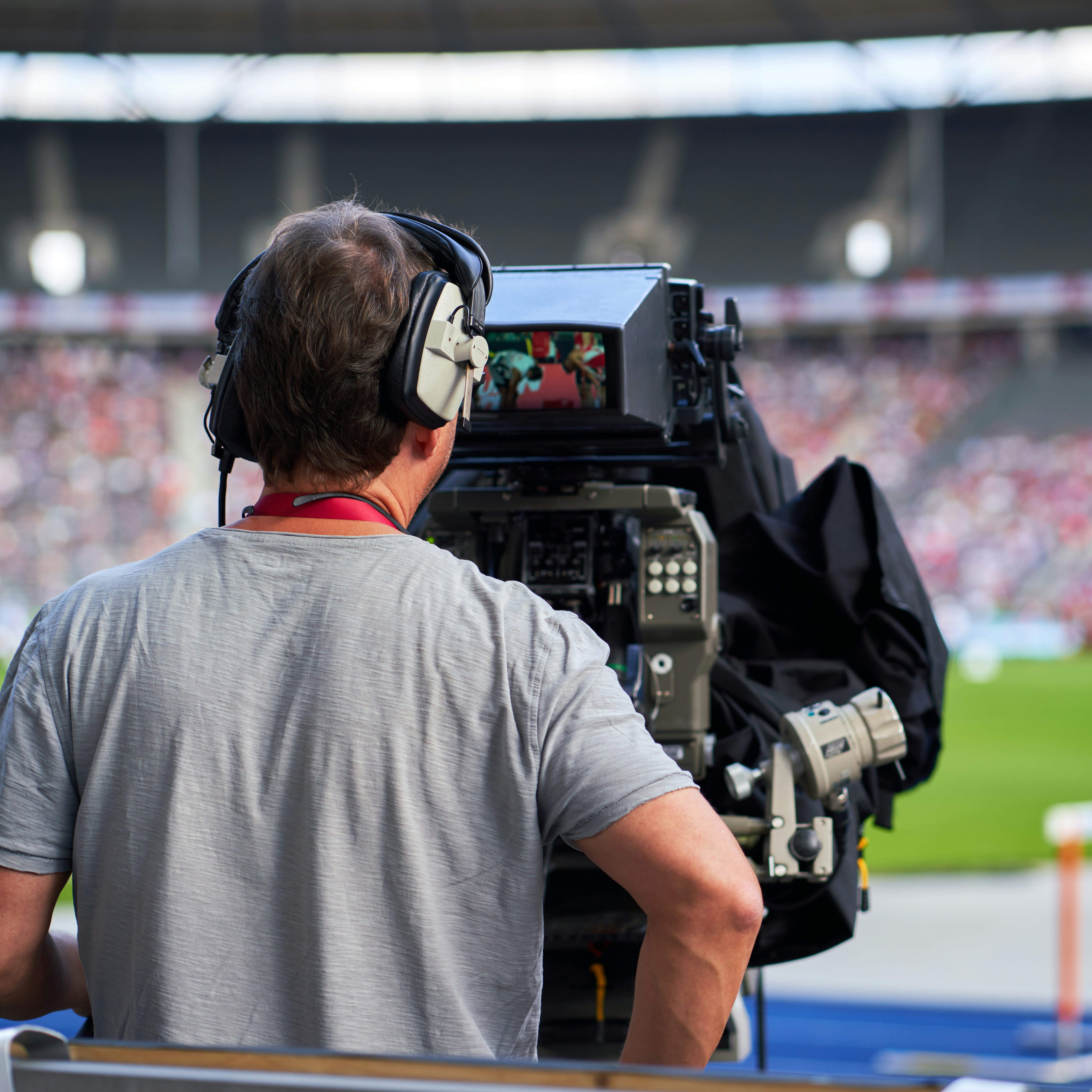 Ein Mann bedient eine große Kamera in einem Fußballstadion.