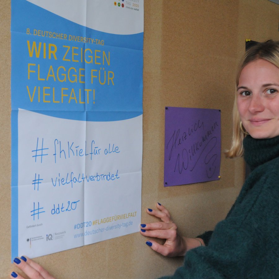 Foto: Meise Frau vor Plakat zu #fh Kiel für alle