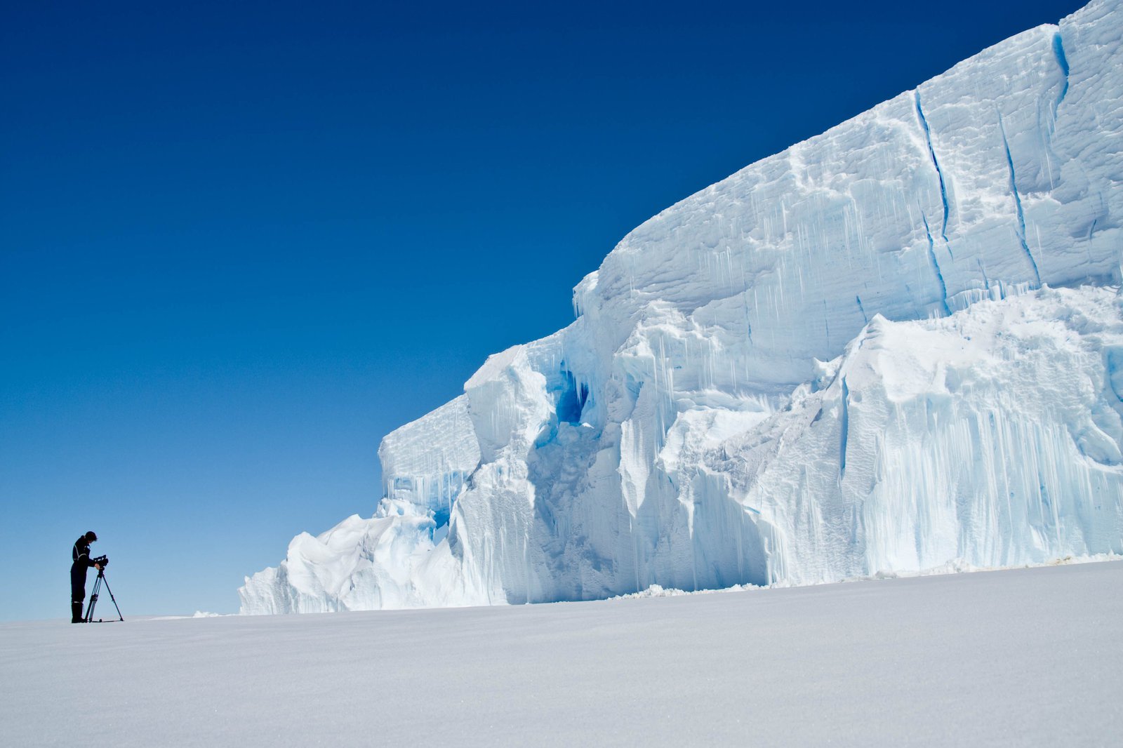 Ein Mann in schwarzem outfir fotografiert einen Gletscher.