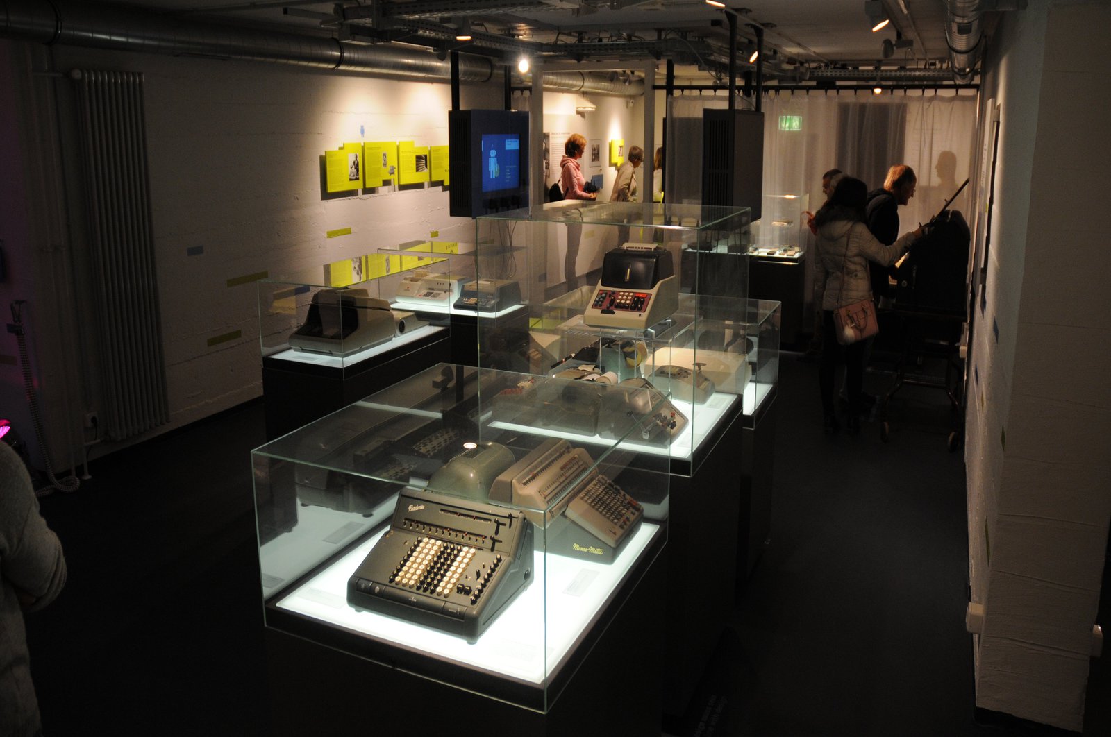 Ein Ausstellungsraum mit alten Computern, die unter Glaskästen geschützt sind.