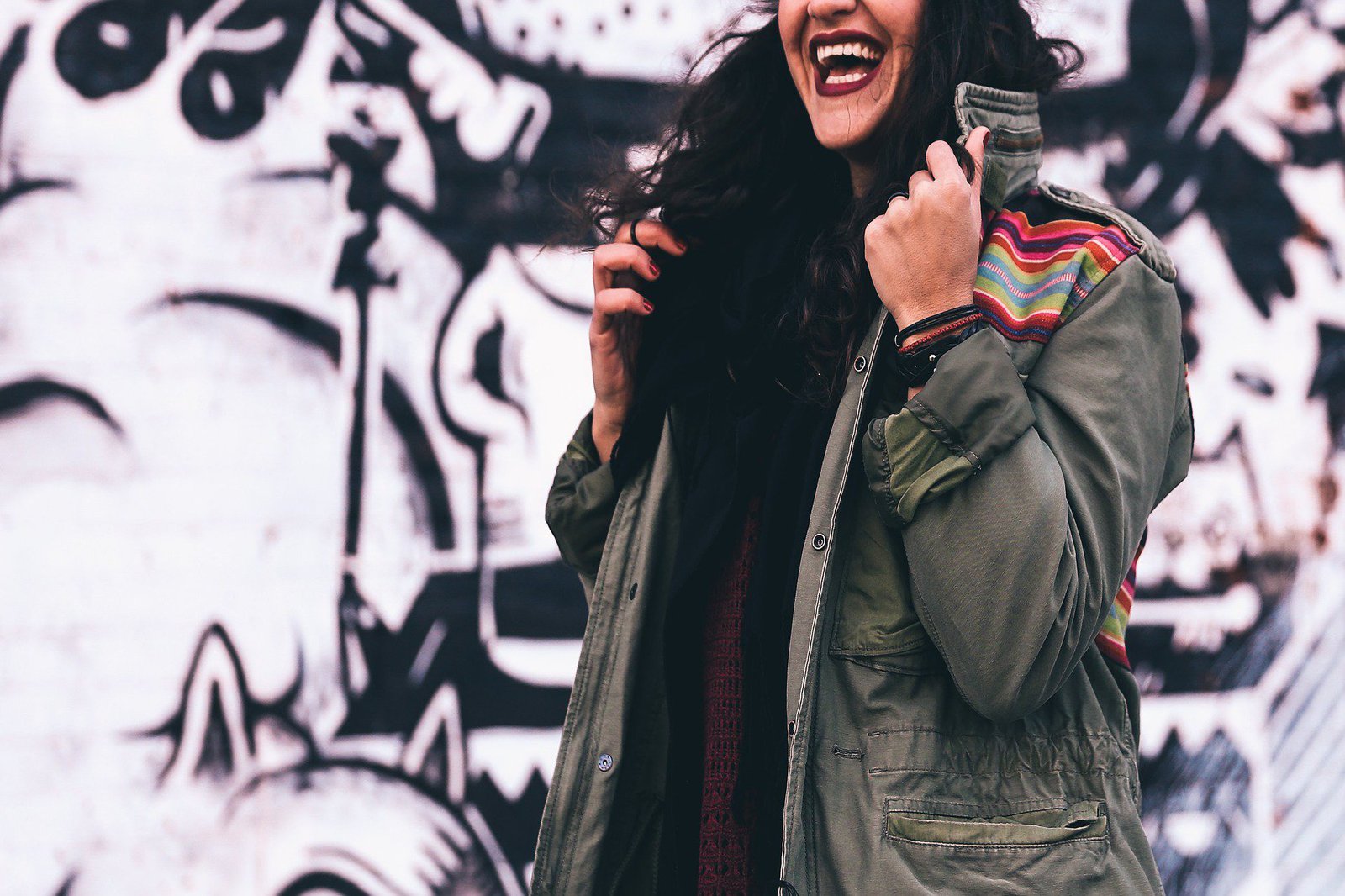 Eine Frau richtet den Kragen ihres grünen Annoraks und lacht dabei.