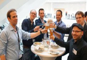 Ein Gruppe Männer stößt zufrieden mit einem Bier an.