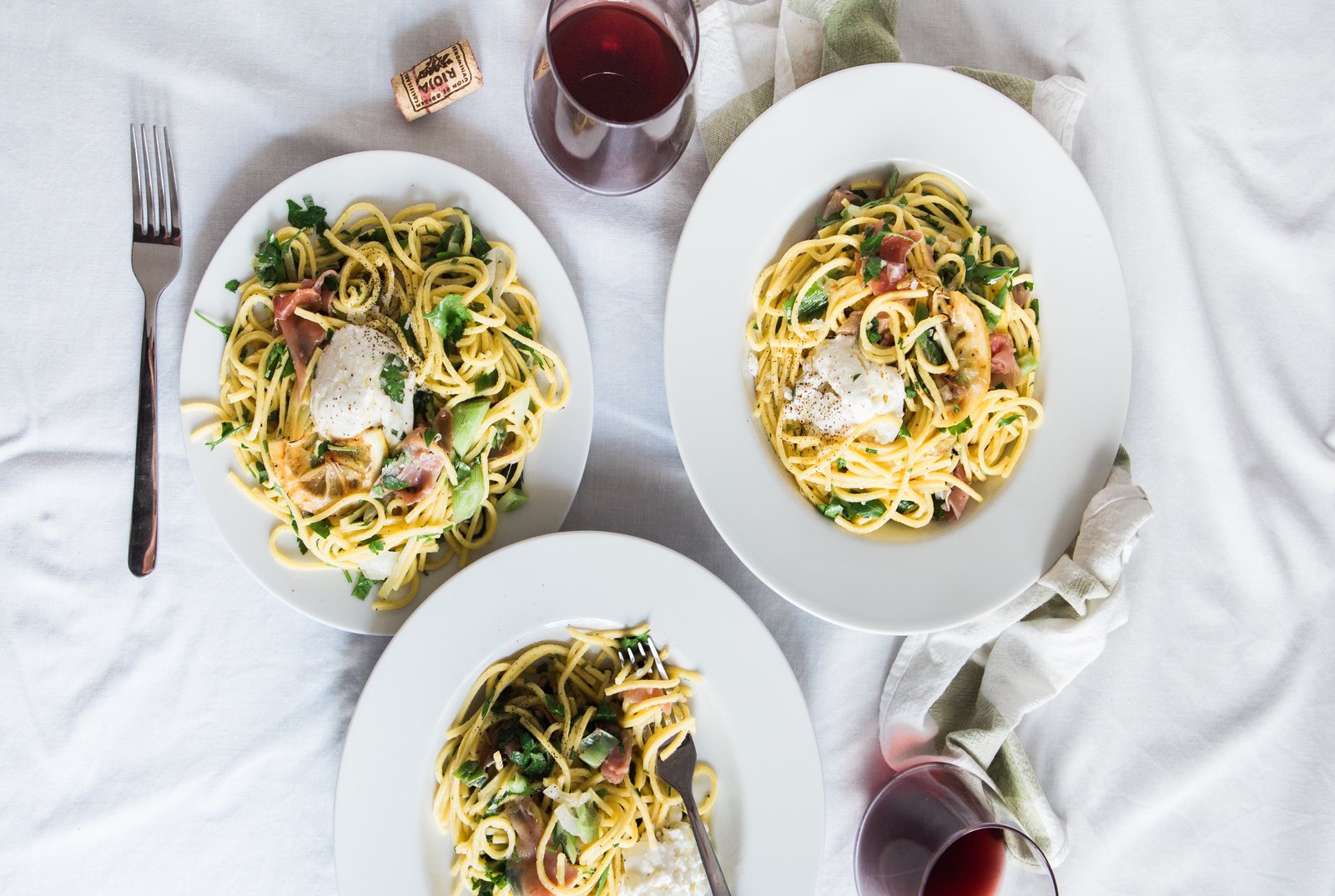 drei mit Pasta befüllte Teller stehen auf einem weissen Laken.