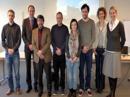 Die Projektgruppe versammelt sich vor der Leinwand, in einem Konferenzraum.