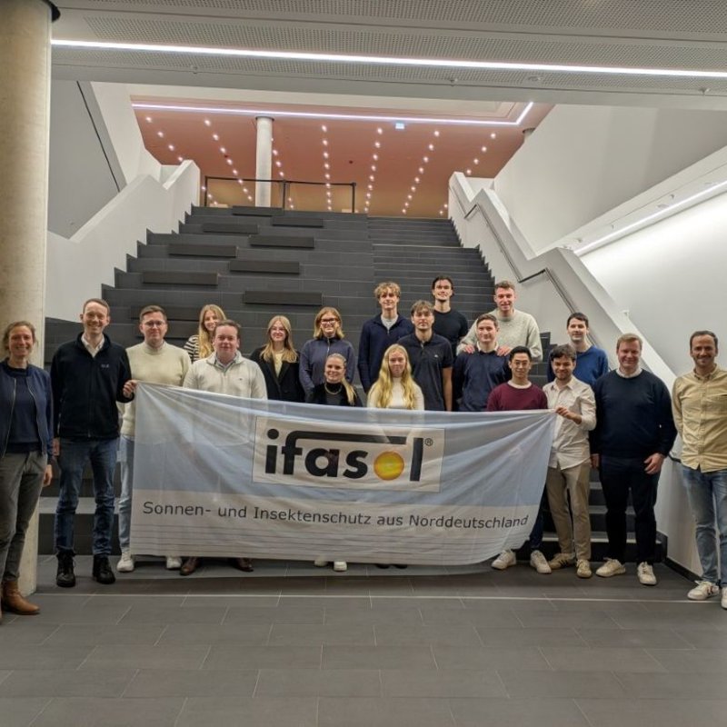 eine Gruppe von Menschen steht im Foyer des Lerndock23 der HAW Kiel und hält eine Fahne mit der Aufschrift ifasol