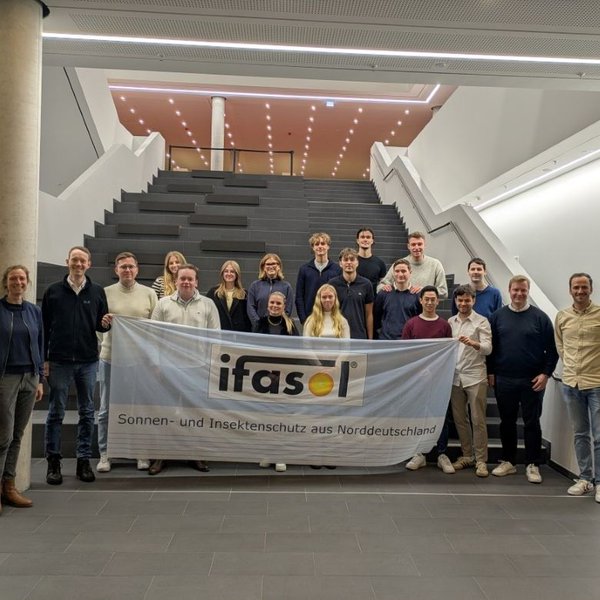 eine Gruppe von Menschen steht im Foyer des Lerndock23 der HAW Kiel und hält eine Fahne mit der Aufschrift ifasol