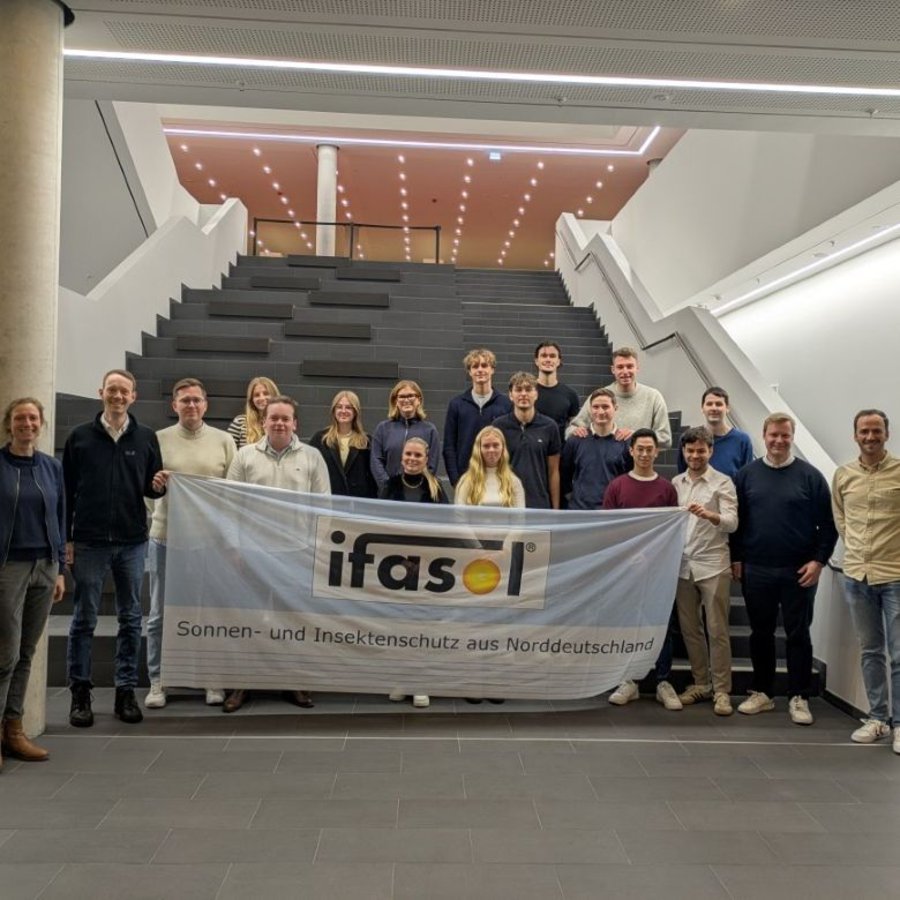 eine Gruppe von Menschen steht im Foyer des Lerndock23 der HAW Kiel und hält eine Fahne mit der Aufschrift ifasol