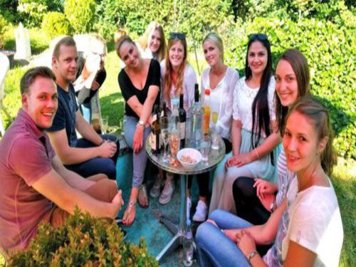 Eine Gruppe Studierender sitzt bei bestem Wetter im Garten und geniesst ein paar kühle Getränke.