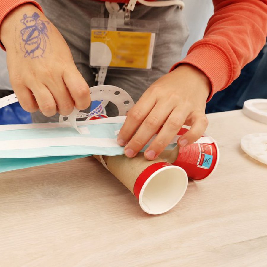 Kinderhände basteln etwas mit Pappbechern und Papier