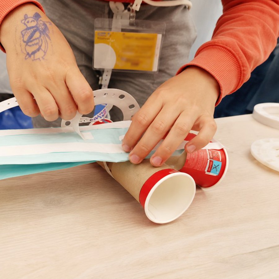Kinderhände basteln etwas mit Pappbechern und Papier