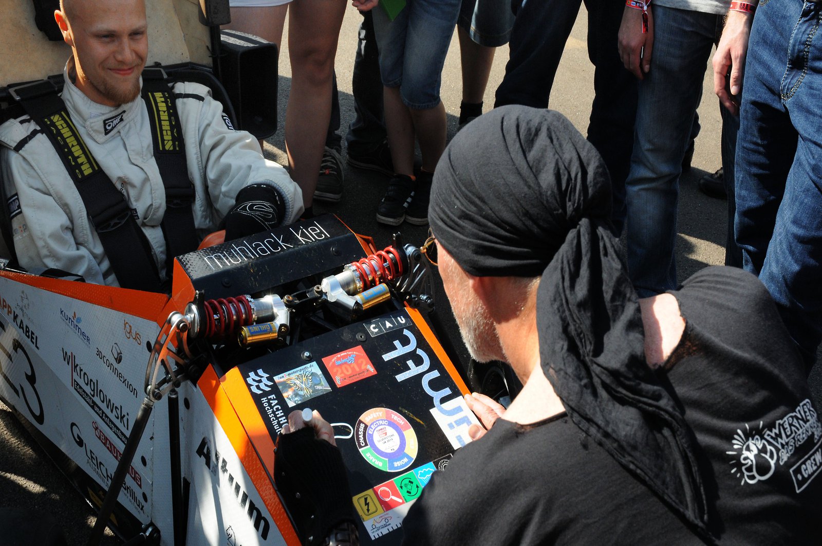 Ein Pilot sitzt freudig in einem Rennwagen und bekommt eine signatur darauf.