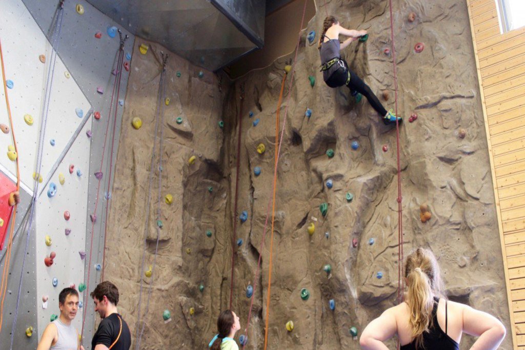 Kleternde wagen den gesicherten Aufstieg einer Kletterwand.