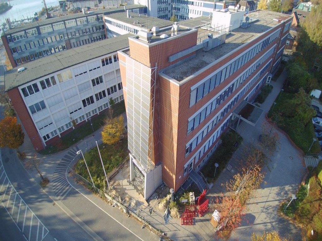Zwei nebeneinander stehende Universitatsgebäude, an der Front des einen sind mehrere Solarplatten angebracht.