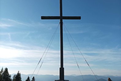 Ein Wanderkreuz vor einem sonnigen blauen Himmel
