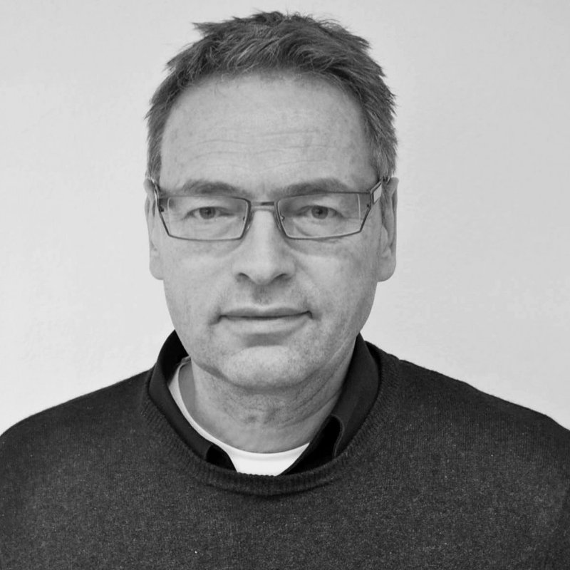Ein Schwarz-Weiss-Bild von einem Mann, der seinen Blick auf die Kamera richtet.