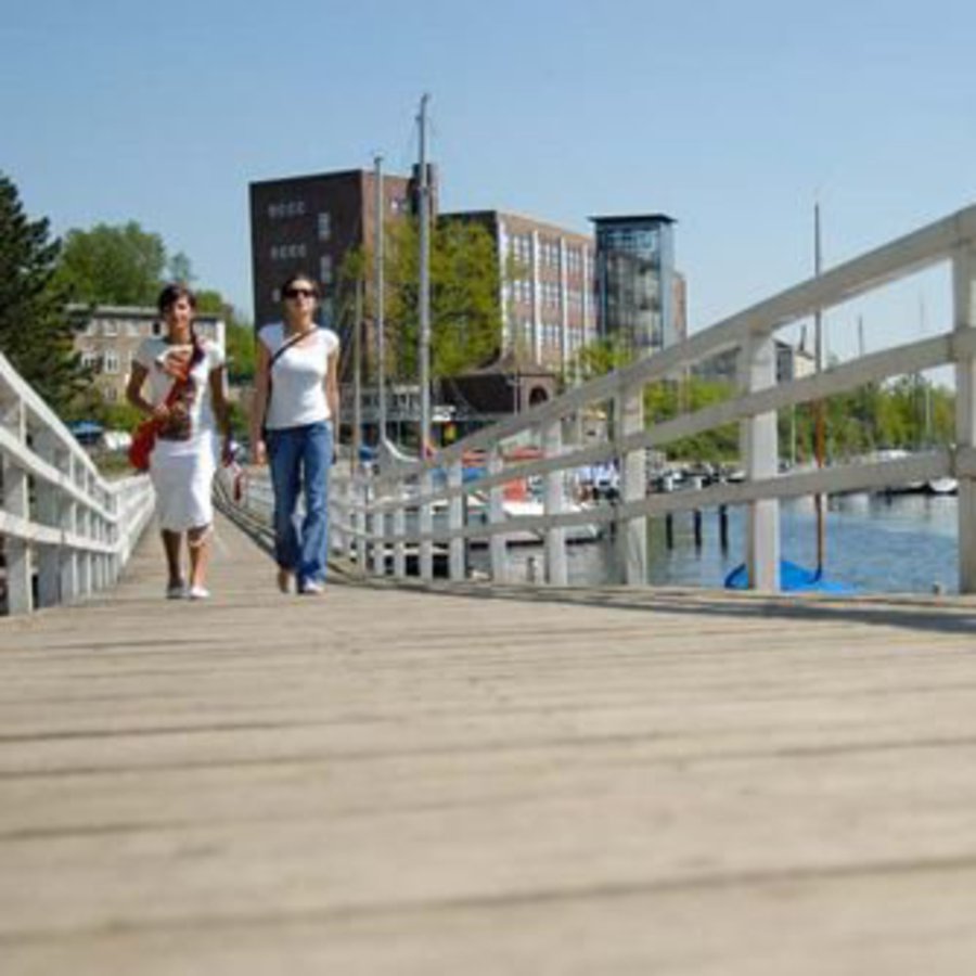 Zwei junge Frauen laufen über einen Holzsteg an der Schwenitine-Mündung.