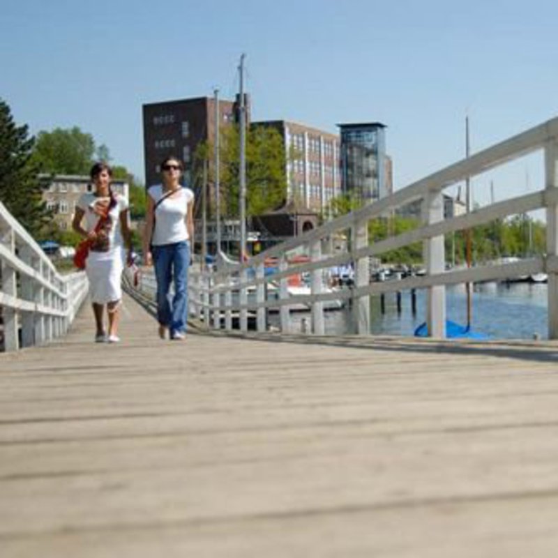 Zwei junge Frauen laufen über einen Holzsteg an der Schwenitine-Mündung.