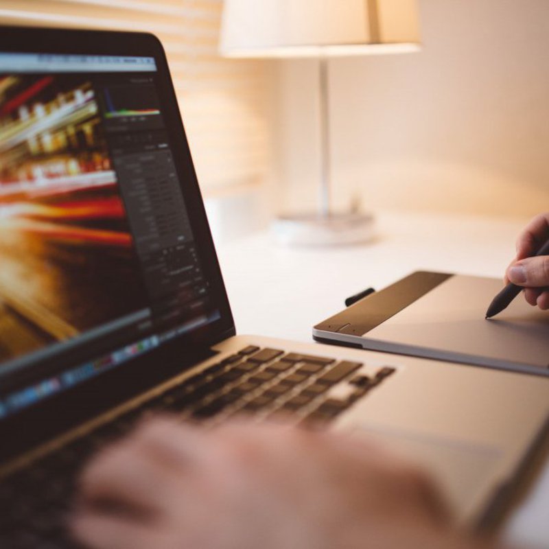 Eine Hand bedient einen Laptop, die andere ein Touchpad und den dazugehörigen Pencil.