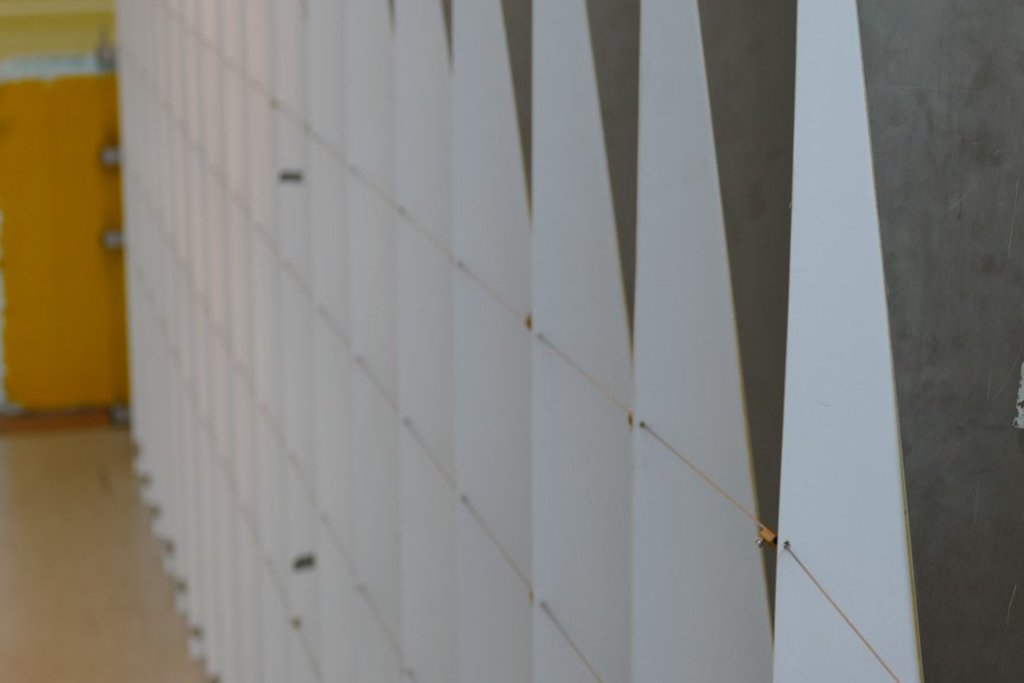 Mehrere weisse Lamellen sind mit Draht verbunden und stellen einen Teil eines Windsimulators dar.