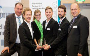 Fünf Männer und eine Fau in Anzügen, posieren gemeinsam für die Kamera.