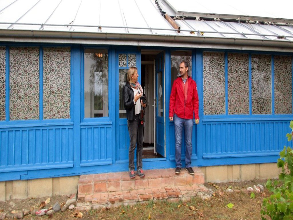 Ein Mann und eine Frau stehen vor einem flachen blauen Haus.