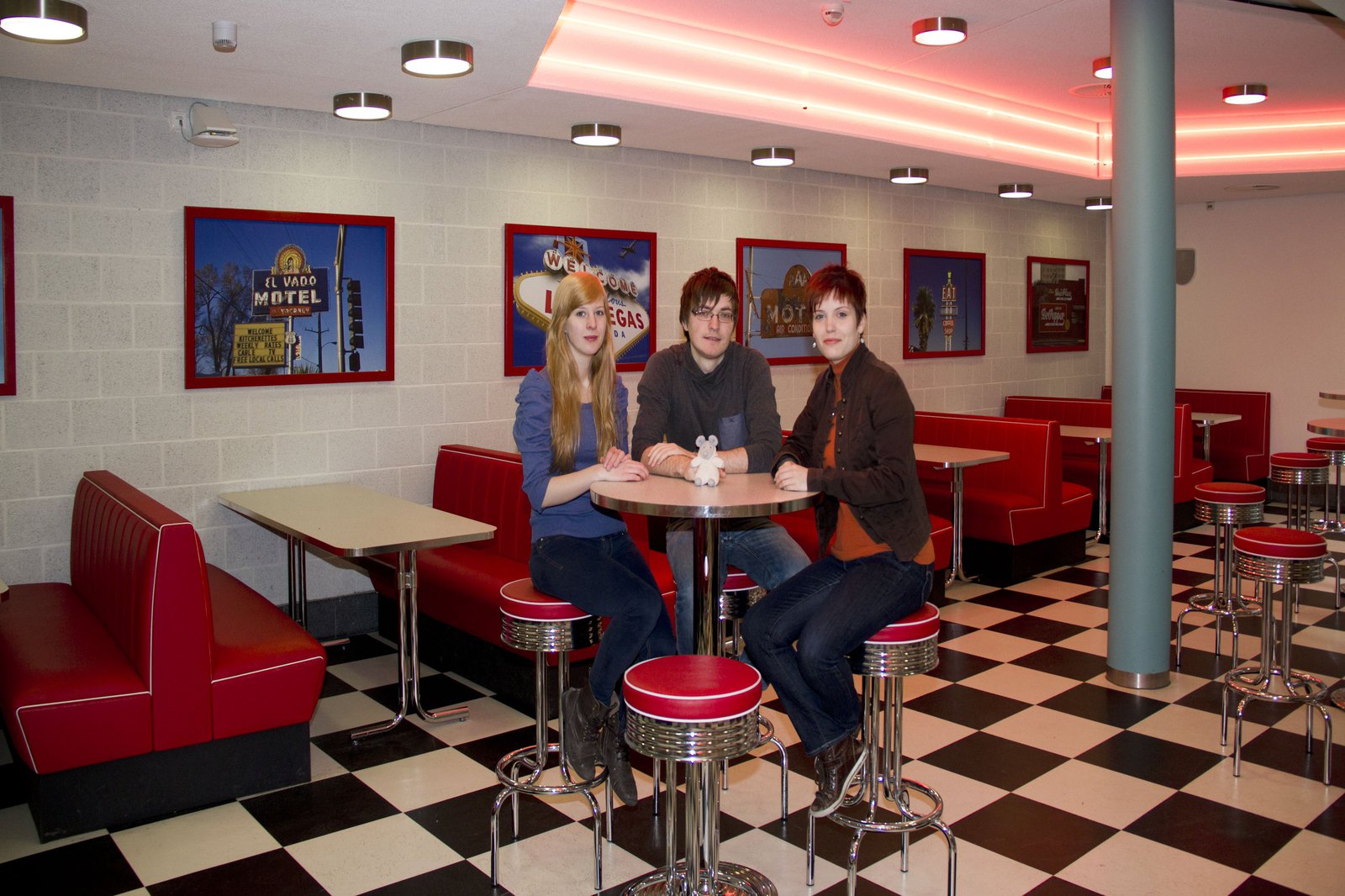 Zwei Frauen und ein Mann sitzen an einem Tisch, im American Diner der FH Kiel.