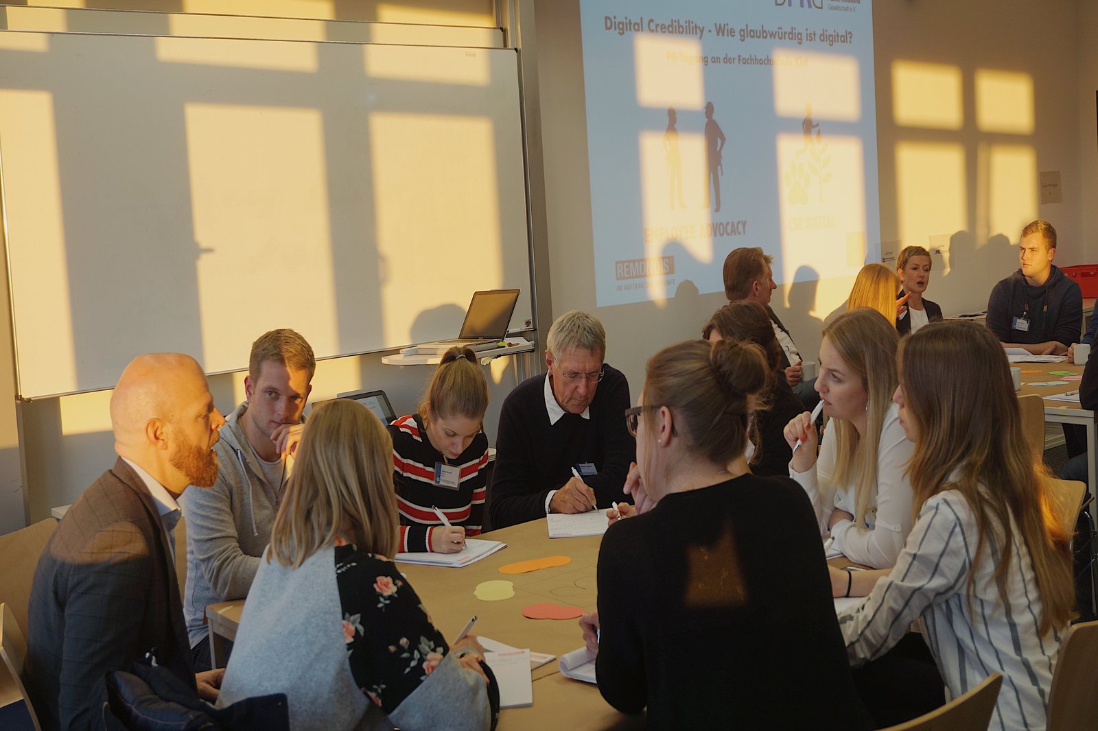 Eine Gruppe Studierender sitzt an einem Tisch und ist am arbeiten.