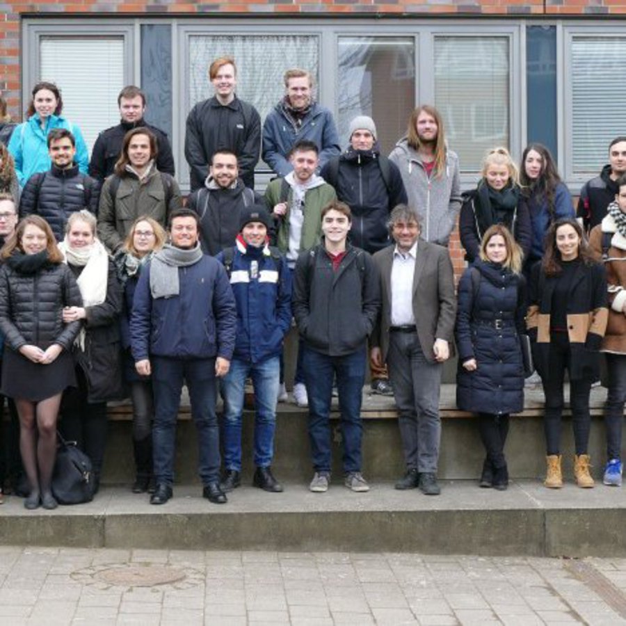 Eine große Gruppe Menschen posiert in Wintermontur vor einem Gebäude.