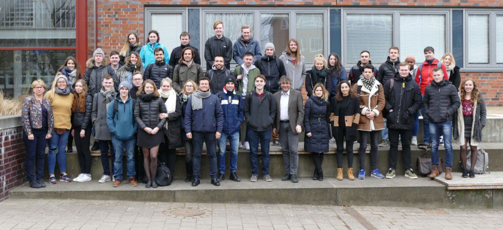 Eine große Gruppe Menschen posiert in Wintermontur vor einem Gebäude.