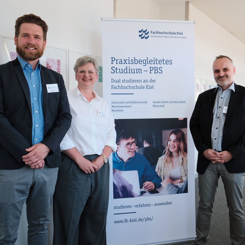 Drei Menschen vor einem Rollup.