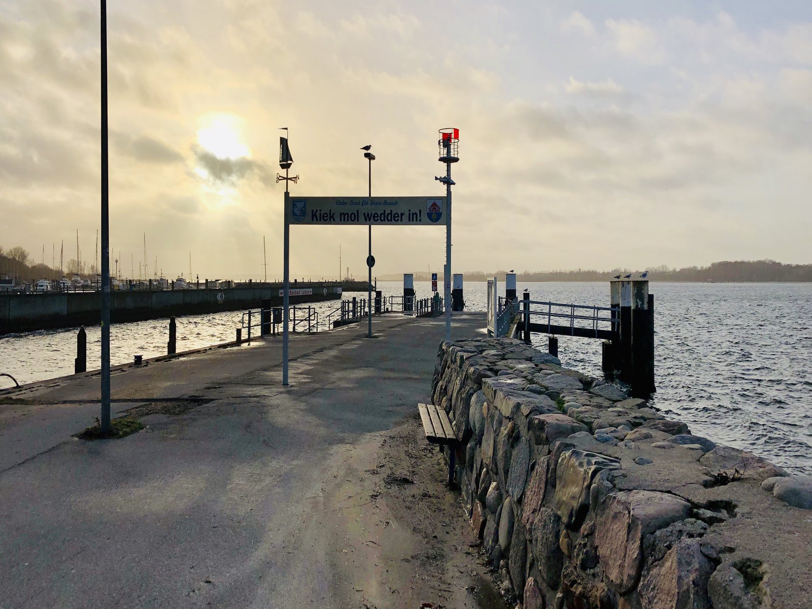 Das Bild zeigt einen Fähranleger an einem sonnig bedeckten Tag.