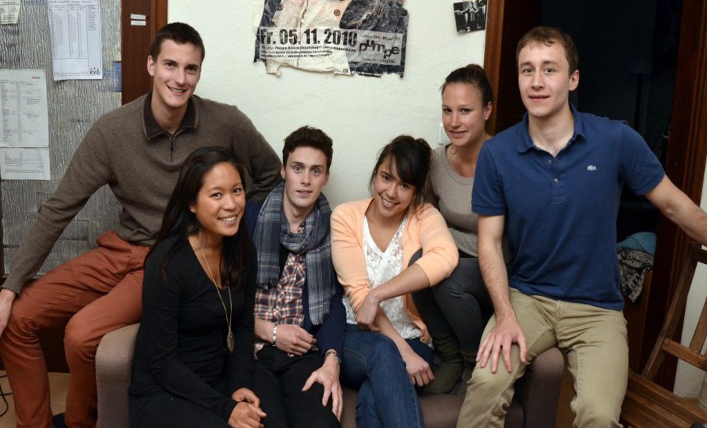 Eine Gruppe internationaler Studierender posiert zusammen in einem Cafe.