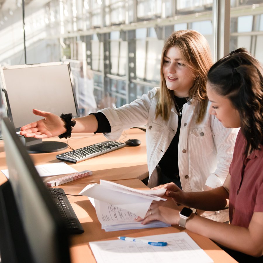 Zwei Frauen sitzen vor einem Computer.