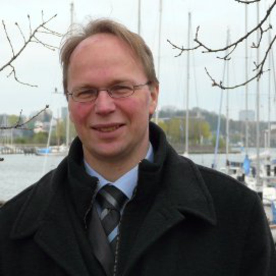 Ein Mann steht Nahe der Schwentinemündung und schaut freundlich in die Kamera.