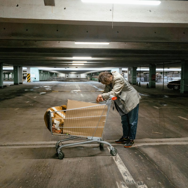 ein wohnungsloser Mann mit einen Einkaufswagen mit seinen Habseligkeiten in einer Tiefgarage