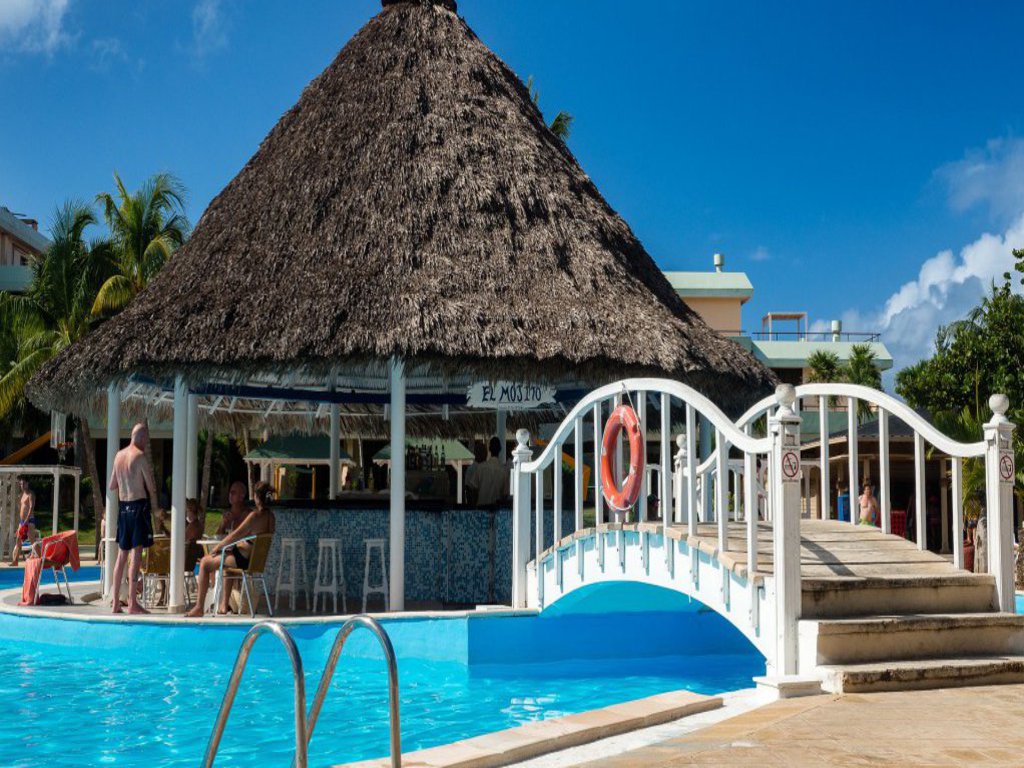 Ein Bungalow auf einer Hotelanlage zu dem Mann über eine Brücke gelangt.