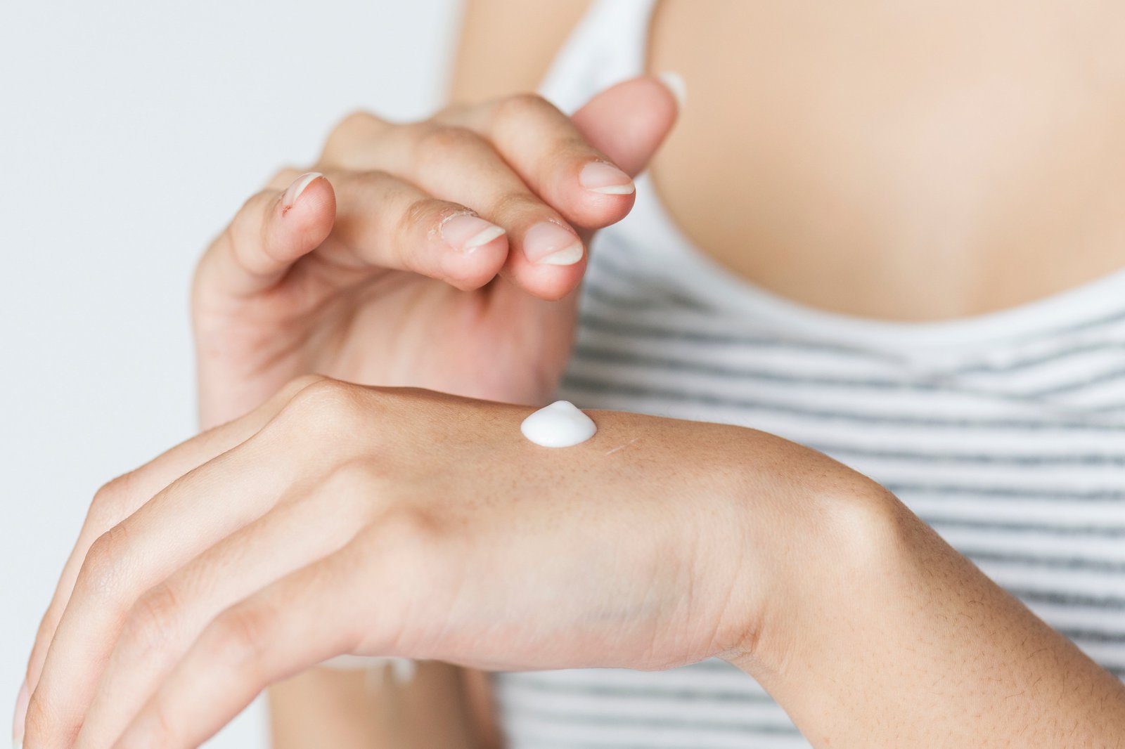 Die Hände einer Frau, kurz davor sich einzucremen.