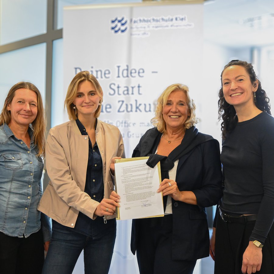 Verteterinnen des StartUp Office und der KielRegeion halten einen Vertrag in die Luft.