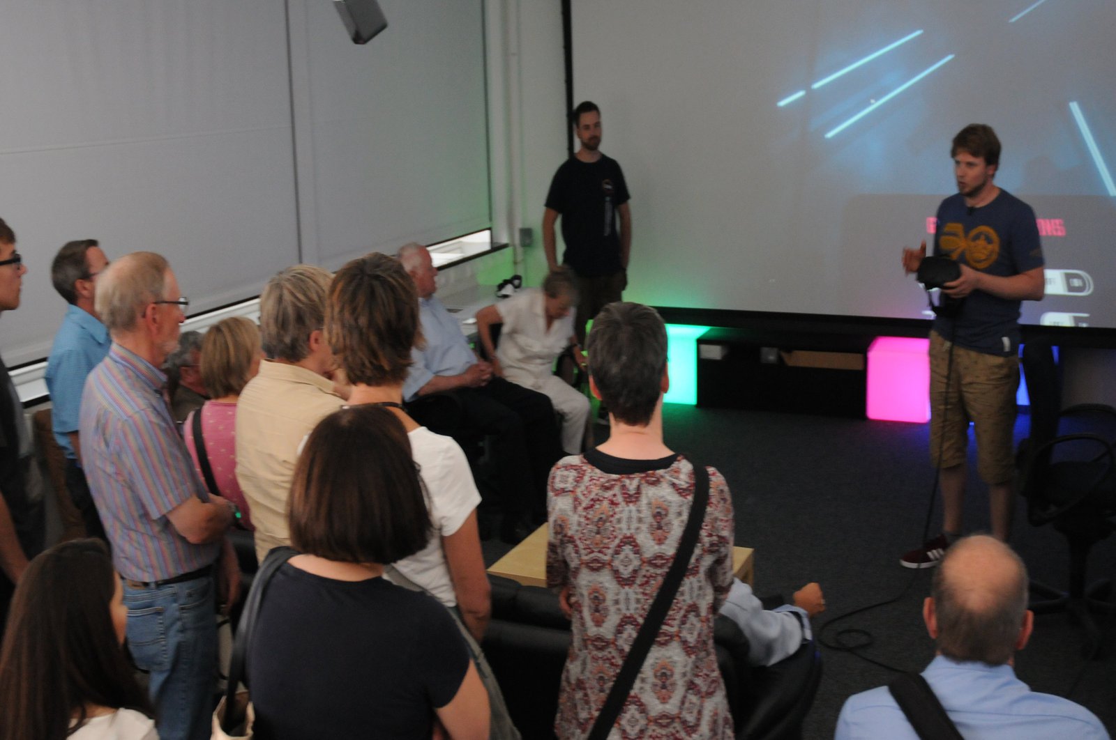 Ein stehendes Publikum hört gespannt einer Präsentation zu.